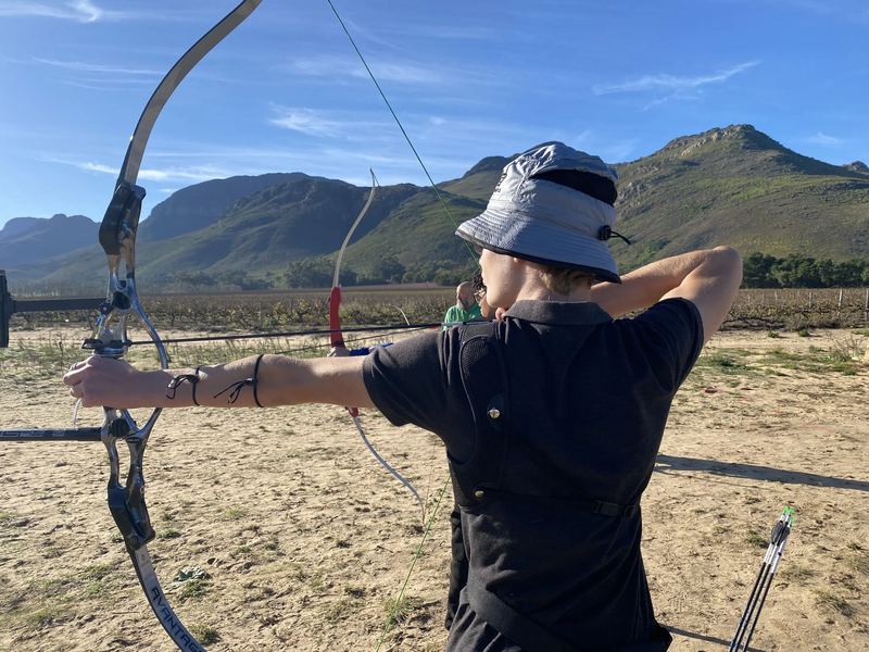 Archer at full draw with the mountains behind